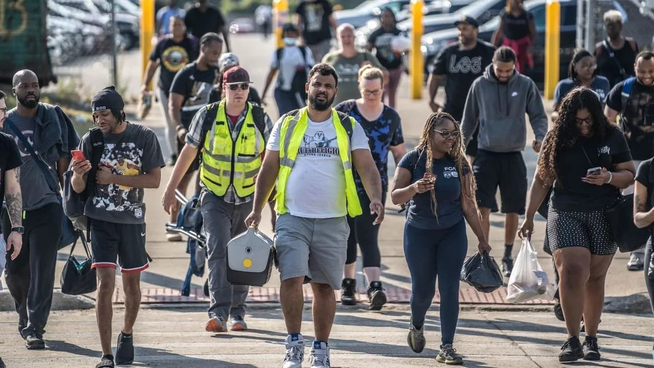 Stellantis workers leaving the plant at shift change, some wearing high-visibility vests