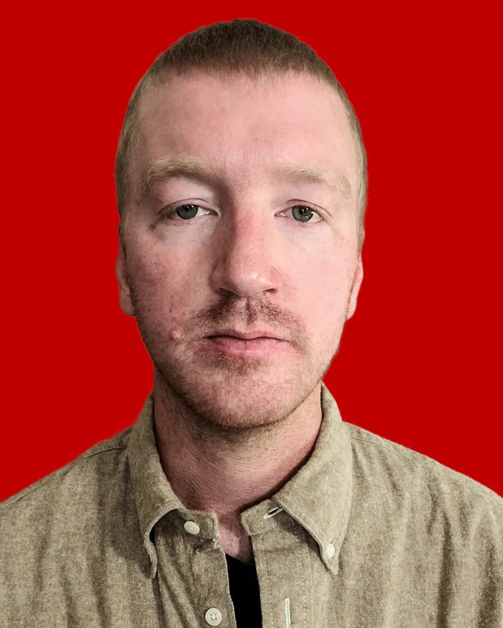 Will Lehman, a man with short reddish-brown hair and a mustache wearing a tan collared shirt, against a solid red background.